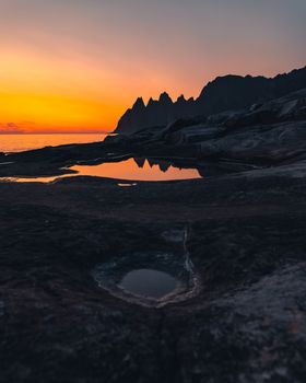 岩石海岸上，日落令人惊叹，海面倒映着余晖，呈现出一片宁静的海景