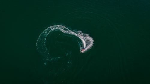Free Dynamic aerial photo of a jet ski making waves on a vast body of water with a swirling pattern. Stock Photo