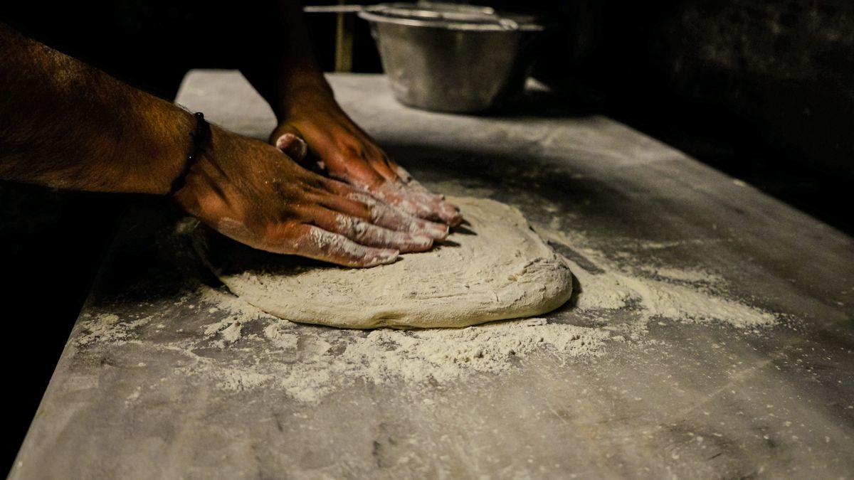 Chef sovando a massa de pizza à mão