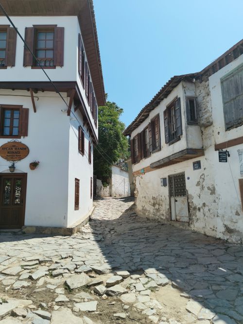 Free Scenic view of a narrow cobblestone street flanked by traditional historic buildings under a clear day sky. Stock Photo