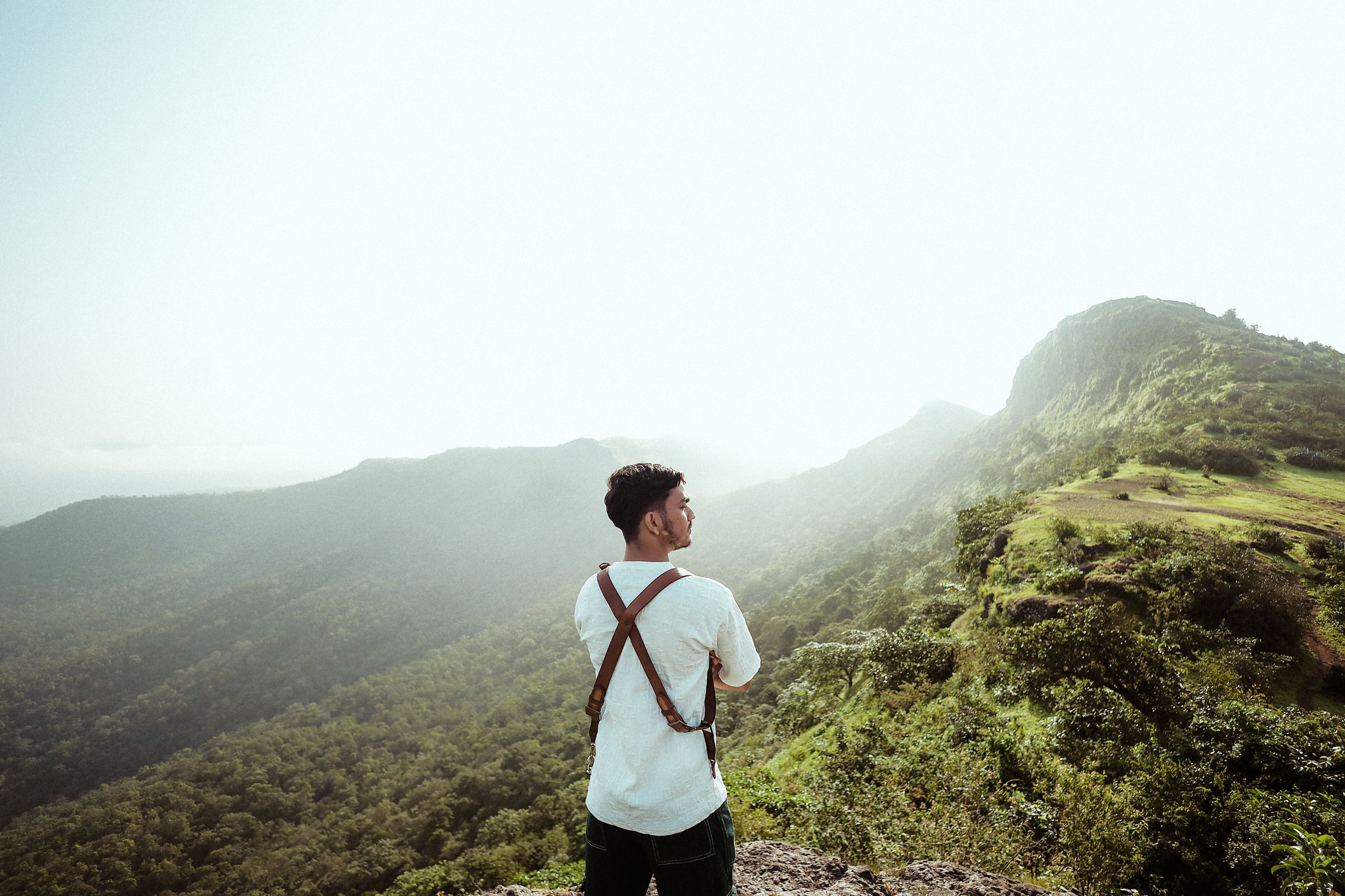A man standing on top of a mountain looking out over the valley · Free ...