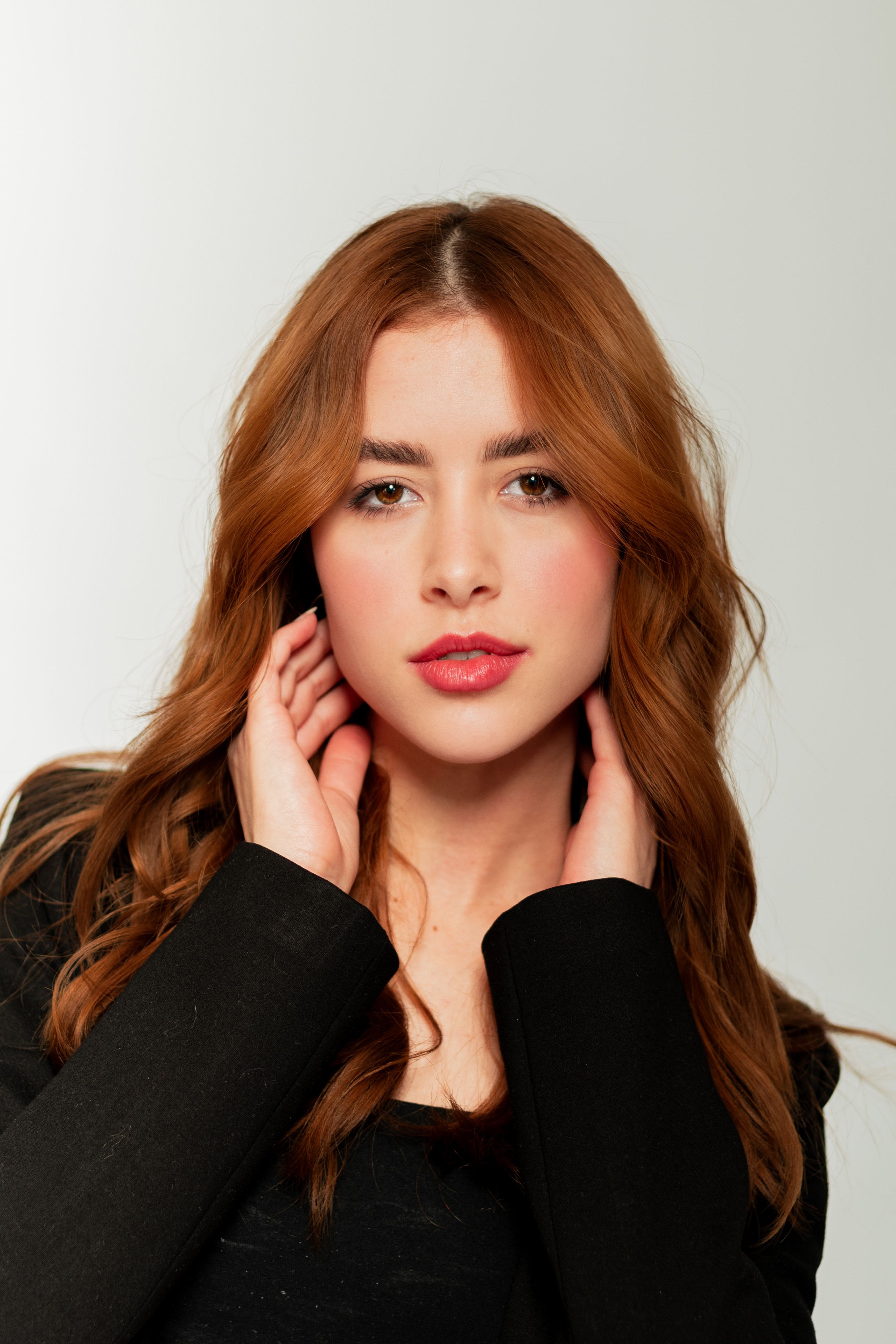 Elegant portrait of a young woman with red hair in a studio setting.