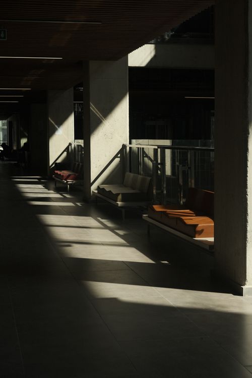 Free Modern indoor hallway with benches and dramatic light shadows. Stock Photo