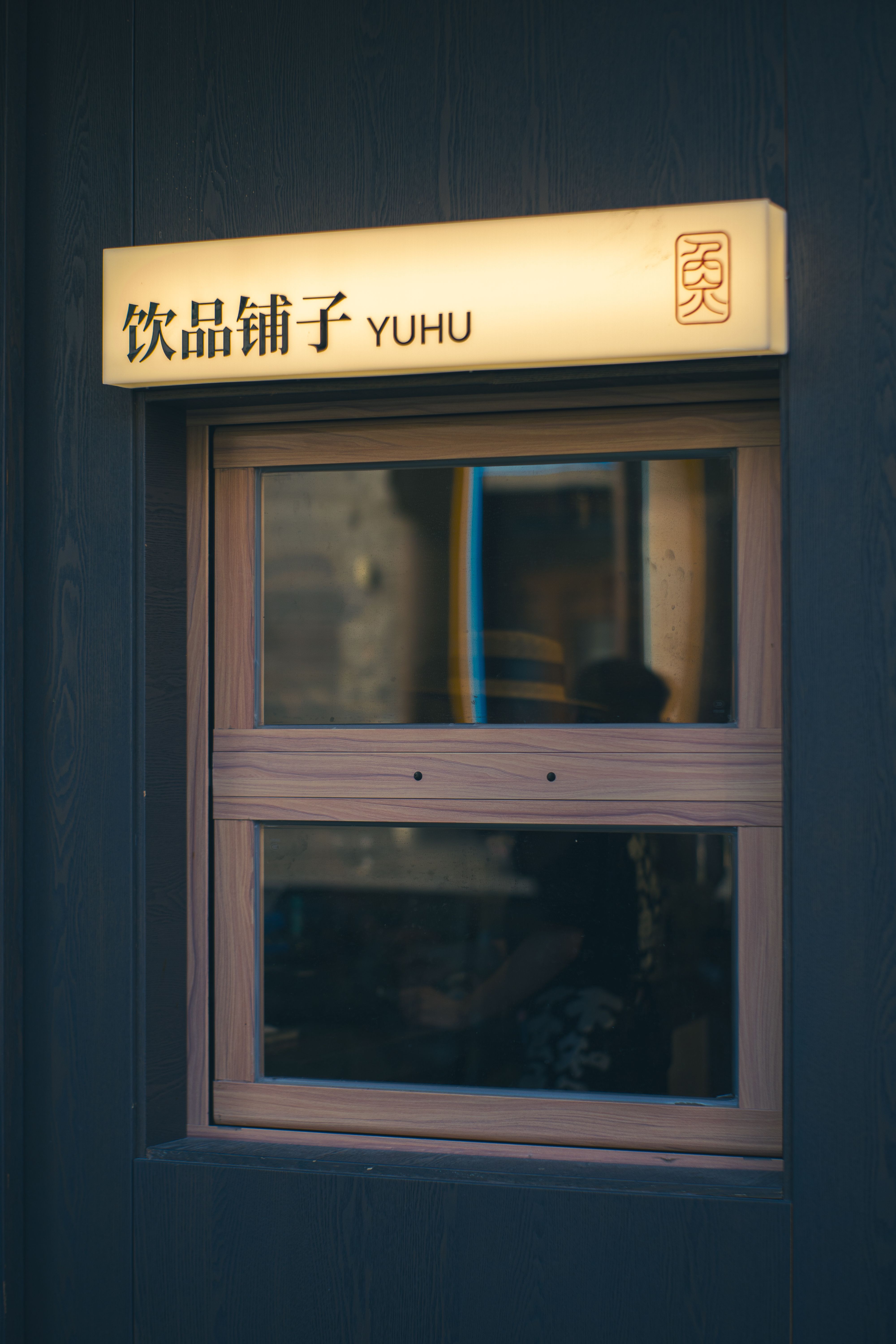 Close-up of a modern shop window with Asian script and signage 'Yuhu' with reflections.