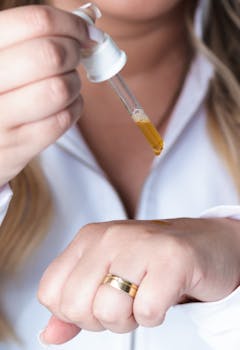 Close-up of a woman applying skincare serum with a dropper.