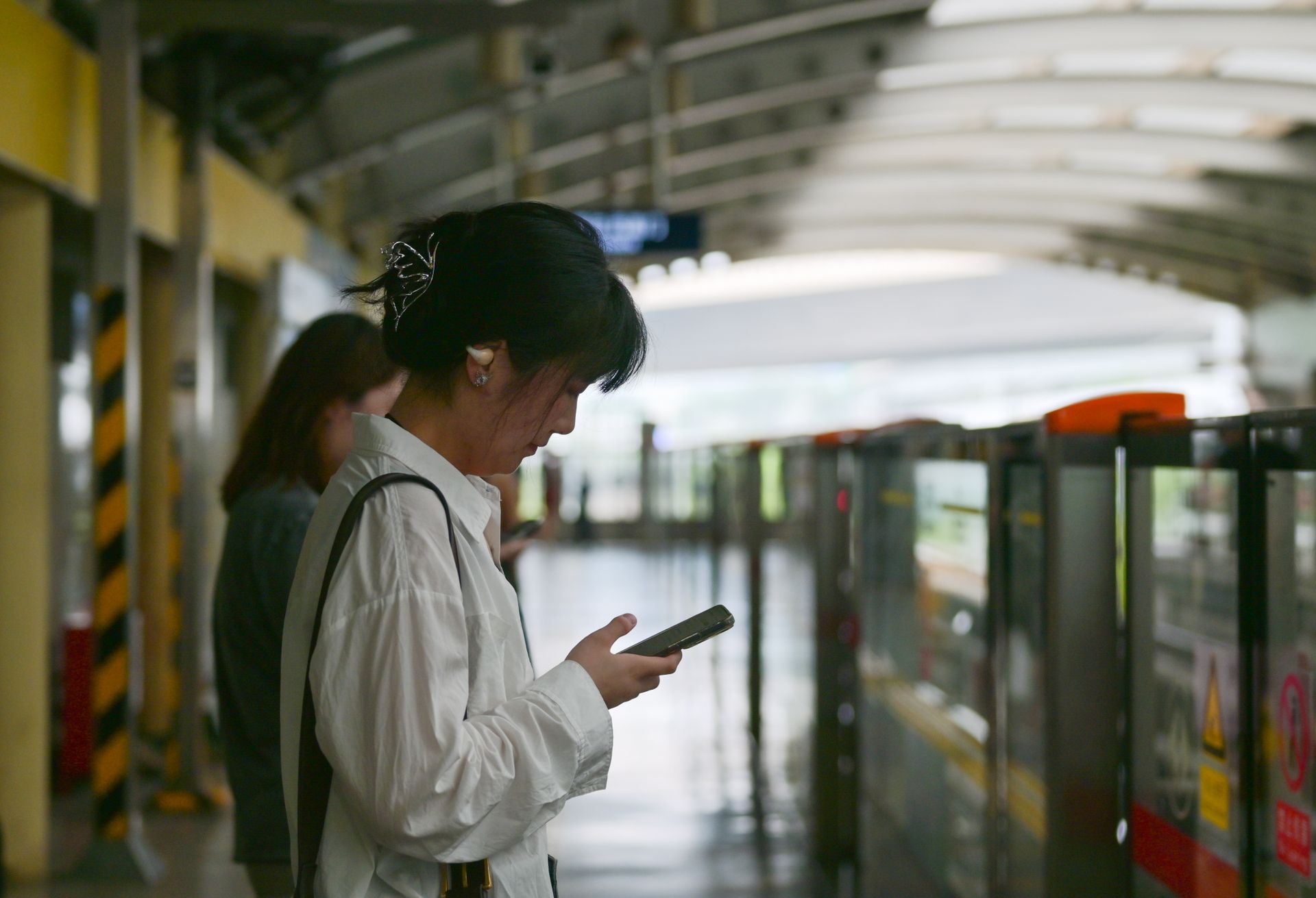 A woman is looking at her cell phone while standing in a train station