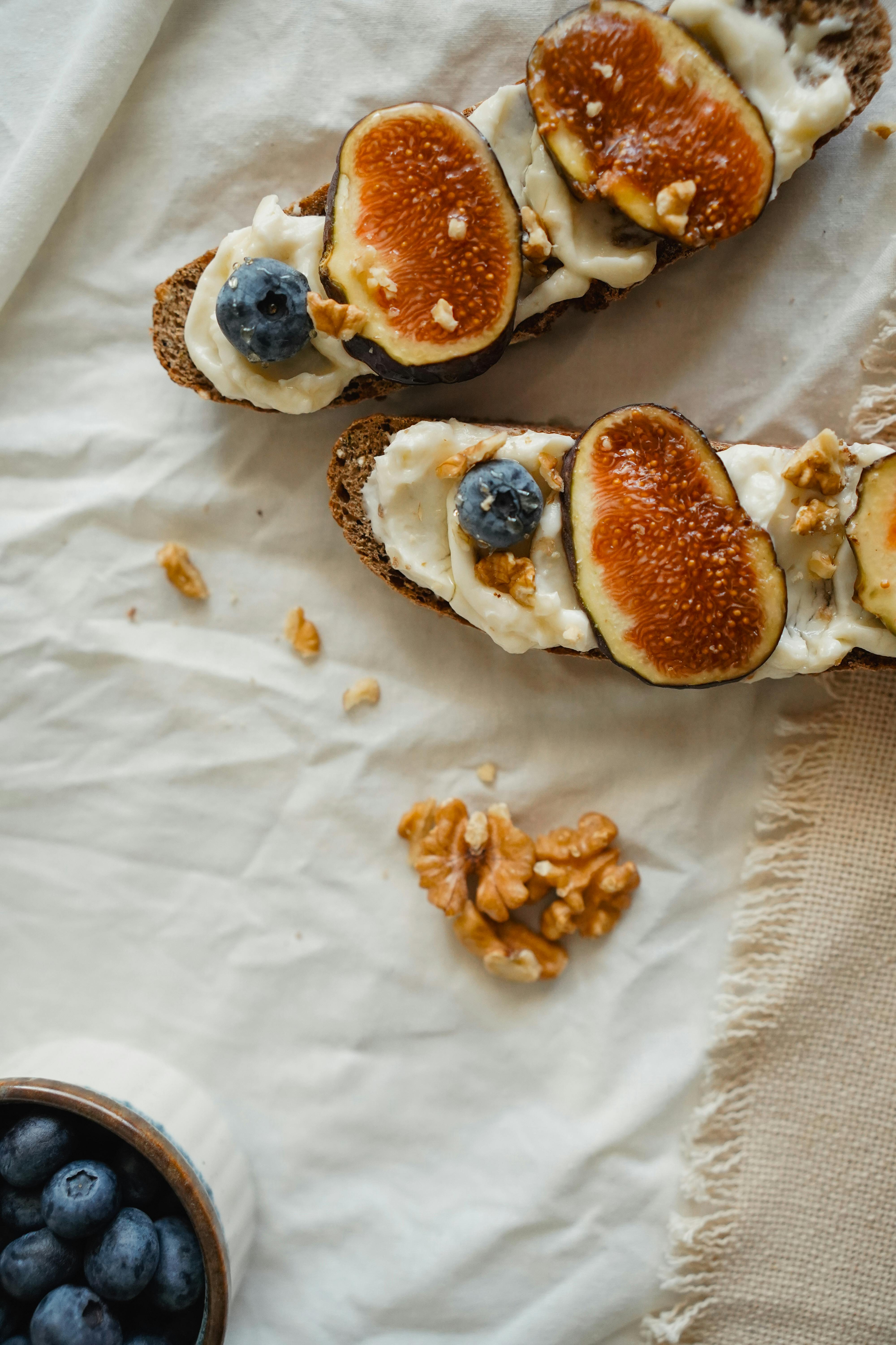 Delicious homemade fig and blueberry toasts with walnuts on rustic linen, perfect for breakfast or snack.