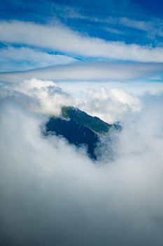 Majestic mountain peak in Reine, Nordland, Norway surrounded by clouds, creating a dramatic scene.