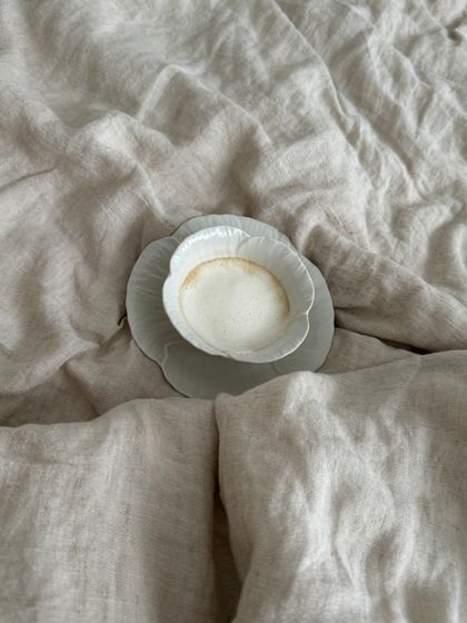 Cup of coffee on soft linen bedding by Aljona Ovtsinnikova on Pexels