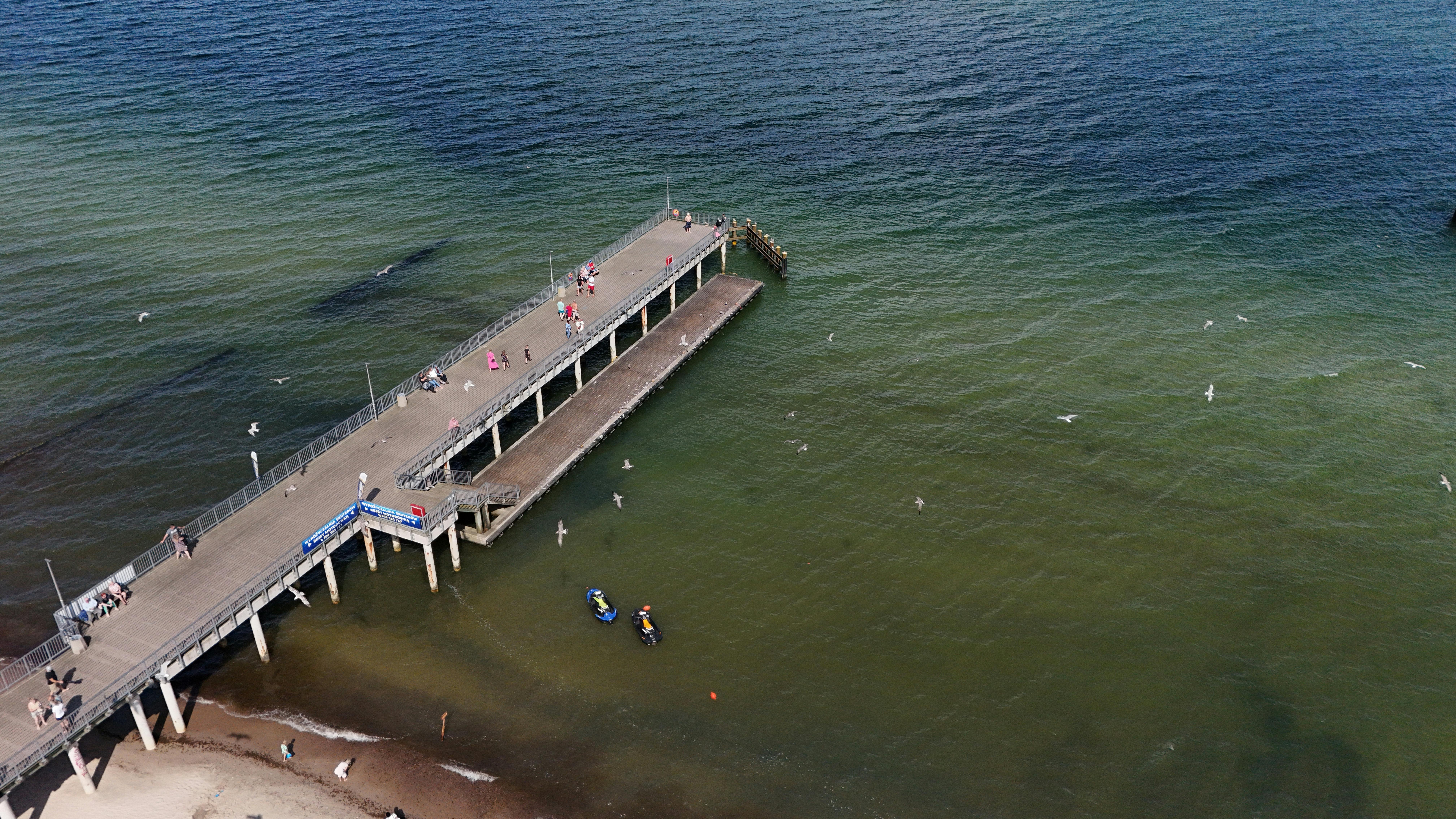 Prescription Goggle Inserts - Aerial view of a pier extending into the ocean, with people walking and seagulls flying.