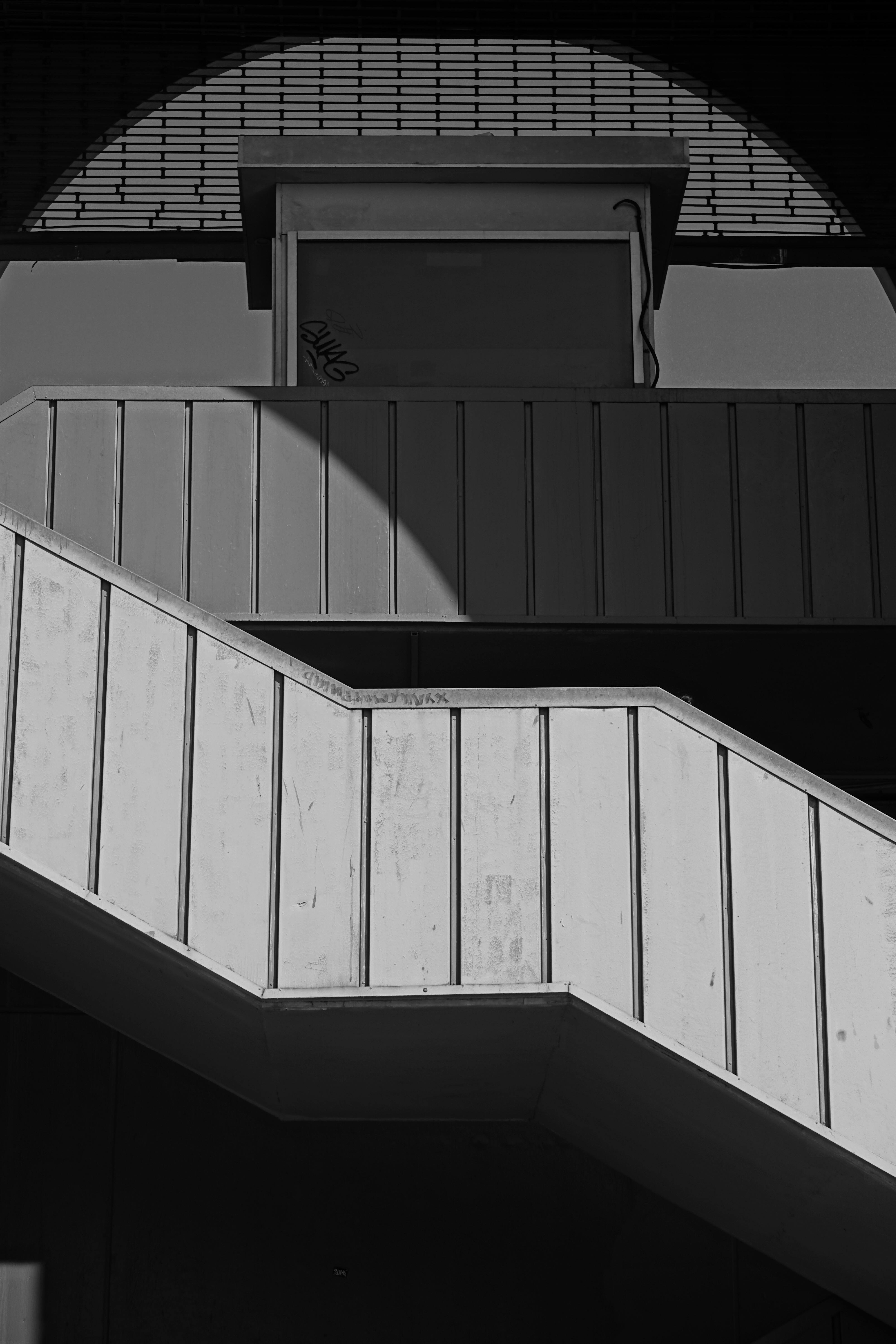 A striking black and white photo of modern staircase and shadow play.