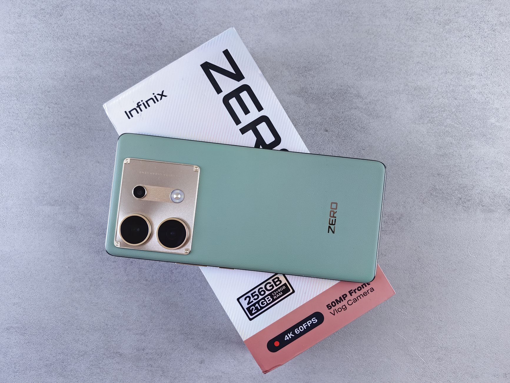 Infinix Zero smartphone resting on its original packaging box against a neutral backdrop.