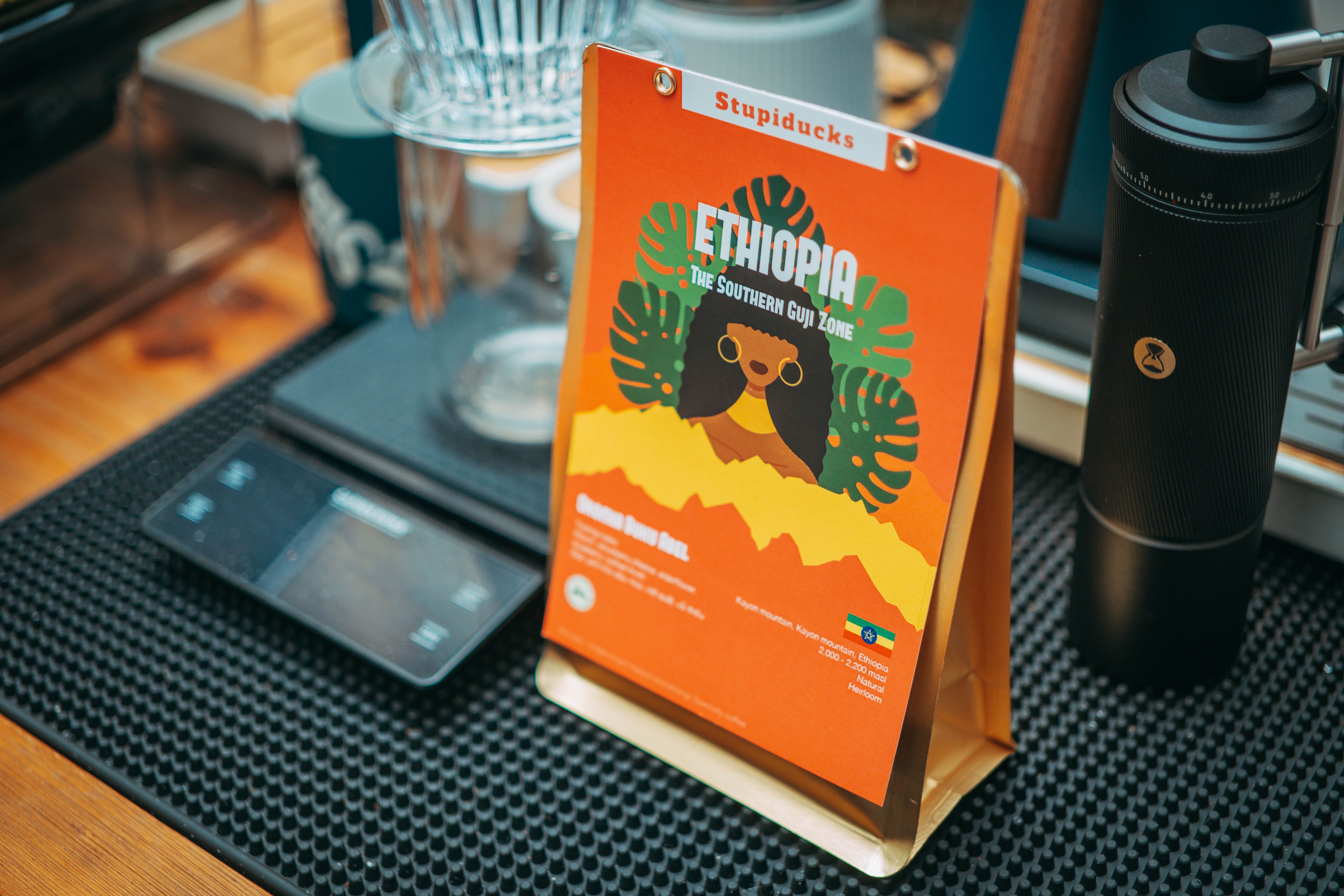 Close-up of Ethiopian coffee brewing set with colorful branding in a cozy cafe.