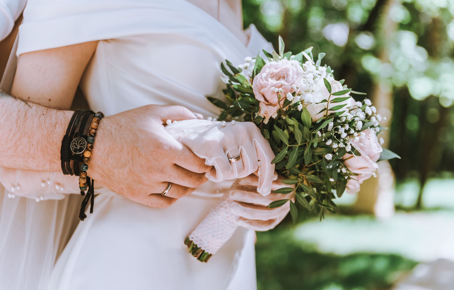 Close-up of a bride and groom holding a floral bouquet, symbolizing love and marriage.