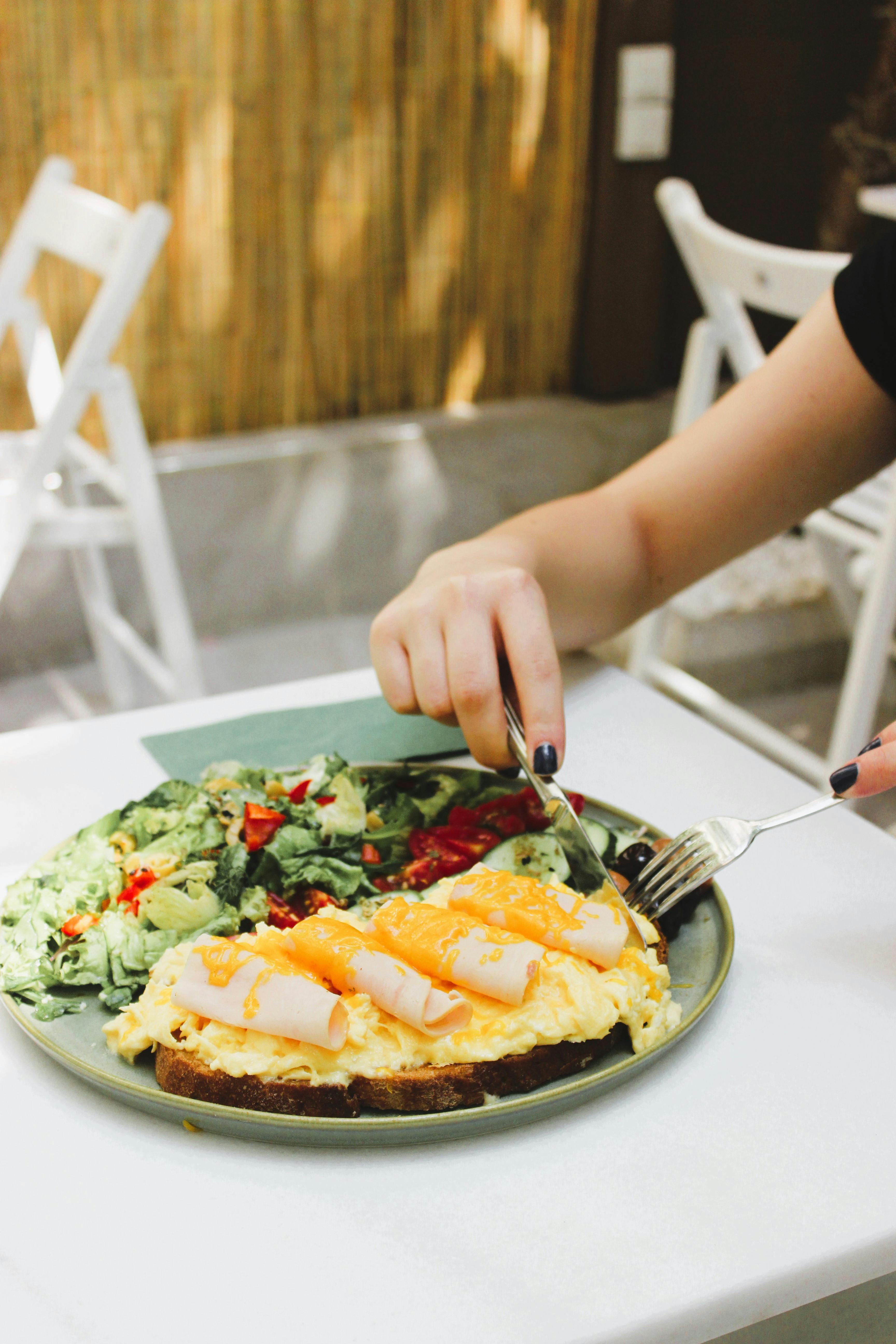A vibrant breakfast plate featuring an omelette and fresh leafy salad on a sunlit table.