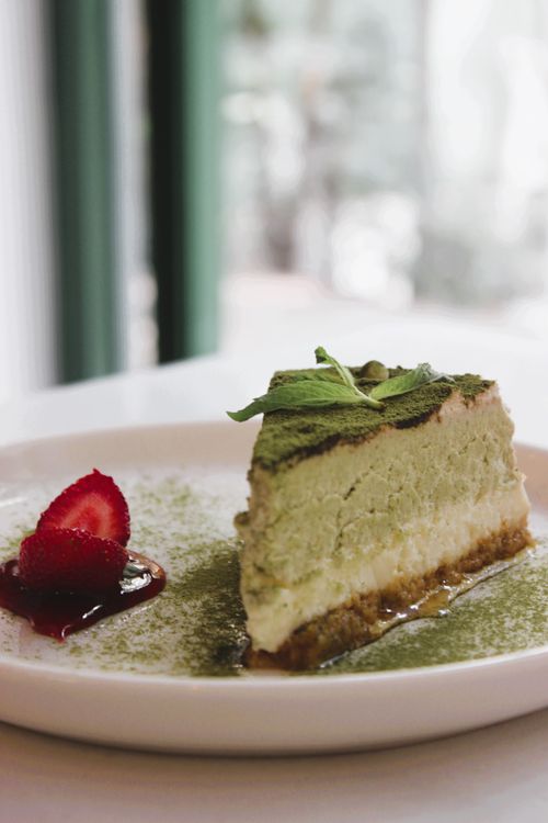 Free Slice of creamy matcha cheesecake with strawberry garnish on a plate. Stock Photo