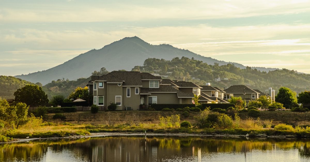 Charming suburban house beside a peaceful lake with mountain views, perfect for serene living.