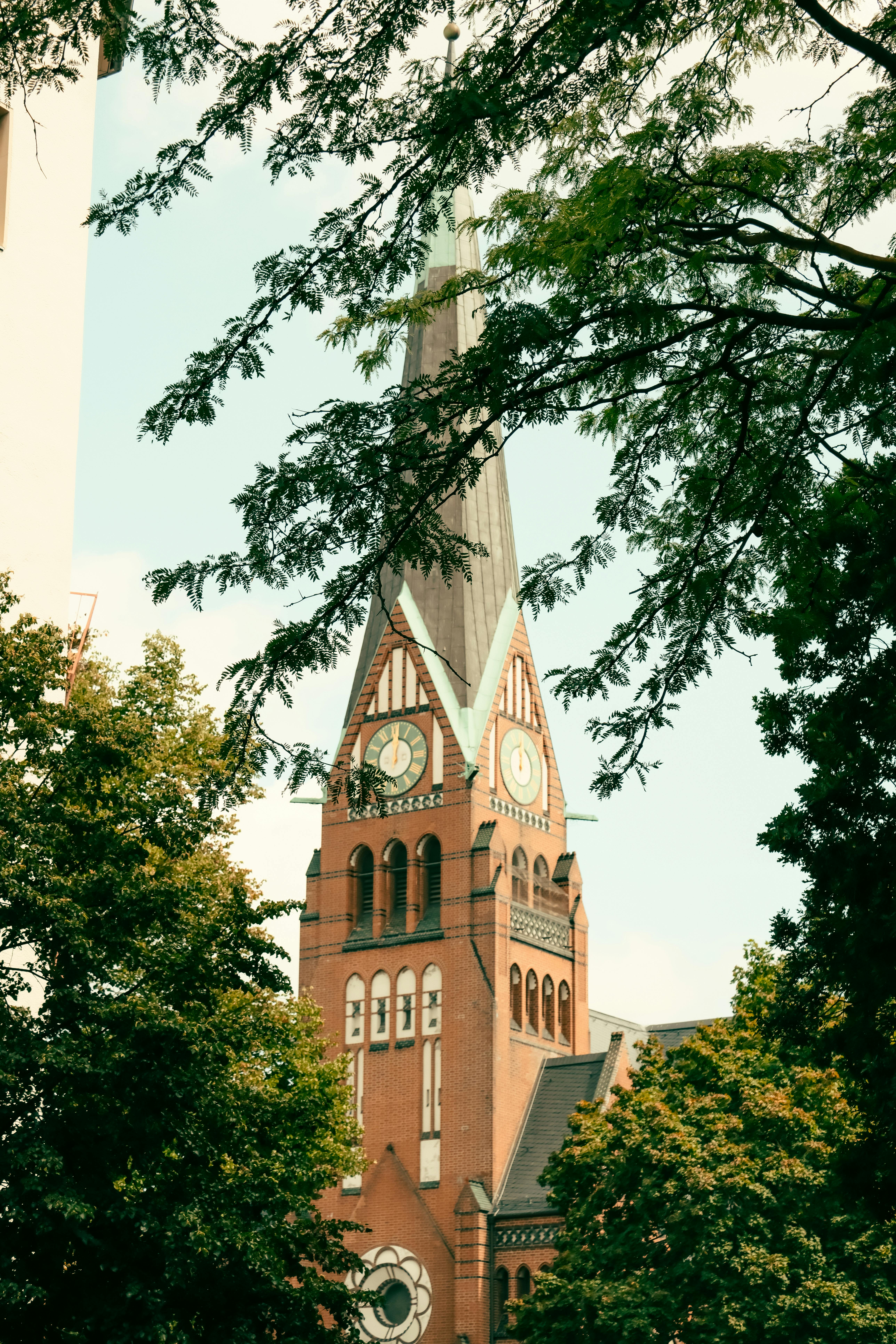 Free A picturesque view of a historic church tower in Berlin surrounded by lush greenery. Stock Photo