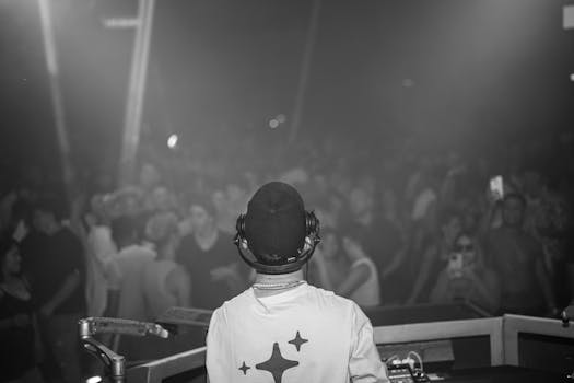 A DJ playing music in front of a vibrant crowd at a night concert.