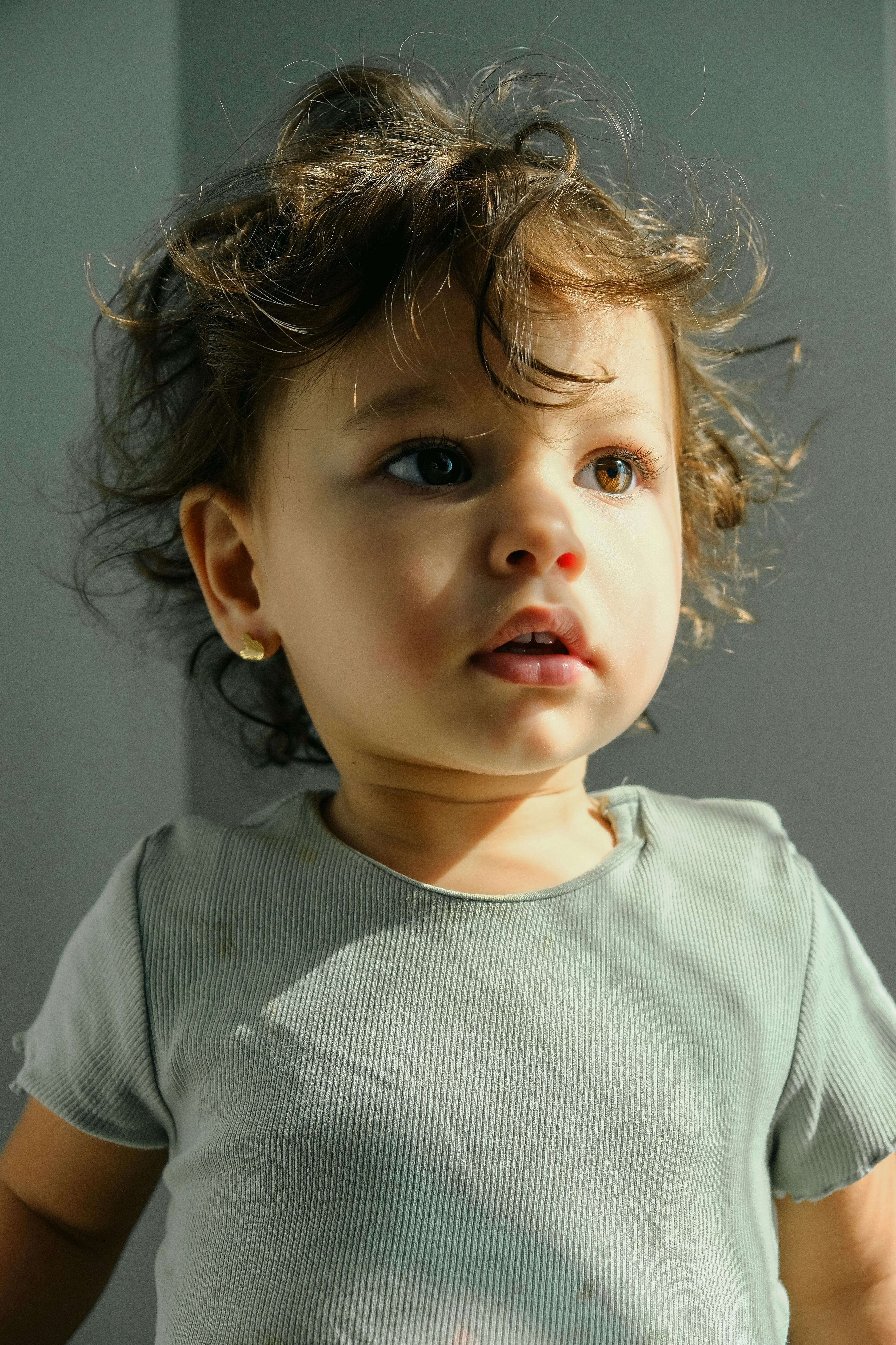a baby with curly hair looking up at the camera