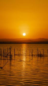 Stunning sunset over calm waters in Albudeite, Murcia with reflective golden hues and silhouetted landscape.