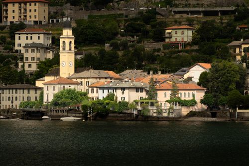 Free Charming Italian village with a church tower by the lake, surrounded by greenery. Stock Photo