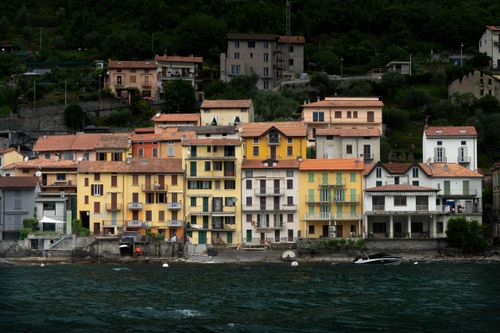 Free Charming colorful buildings line the waterfront of Lake Como, Italy, showcasing traditional Mediterranean architecture. Stock Photo