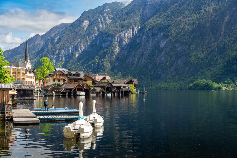 Orașul Hallstatt văzut de pe malul lacului, cu casele colorate reflectate în apă