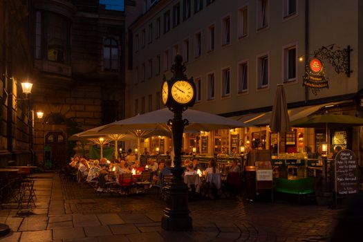 People dining outdoors at a cozy cafe in Dresden under warm evening lights.