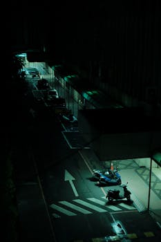 A moody, atmospheric view of a deserted city street lit by streetlights at night.