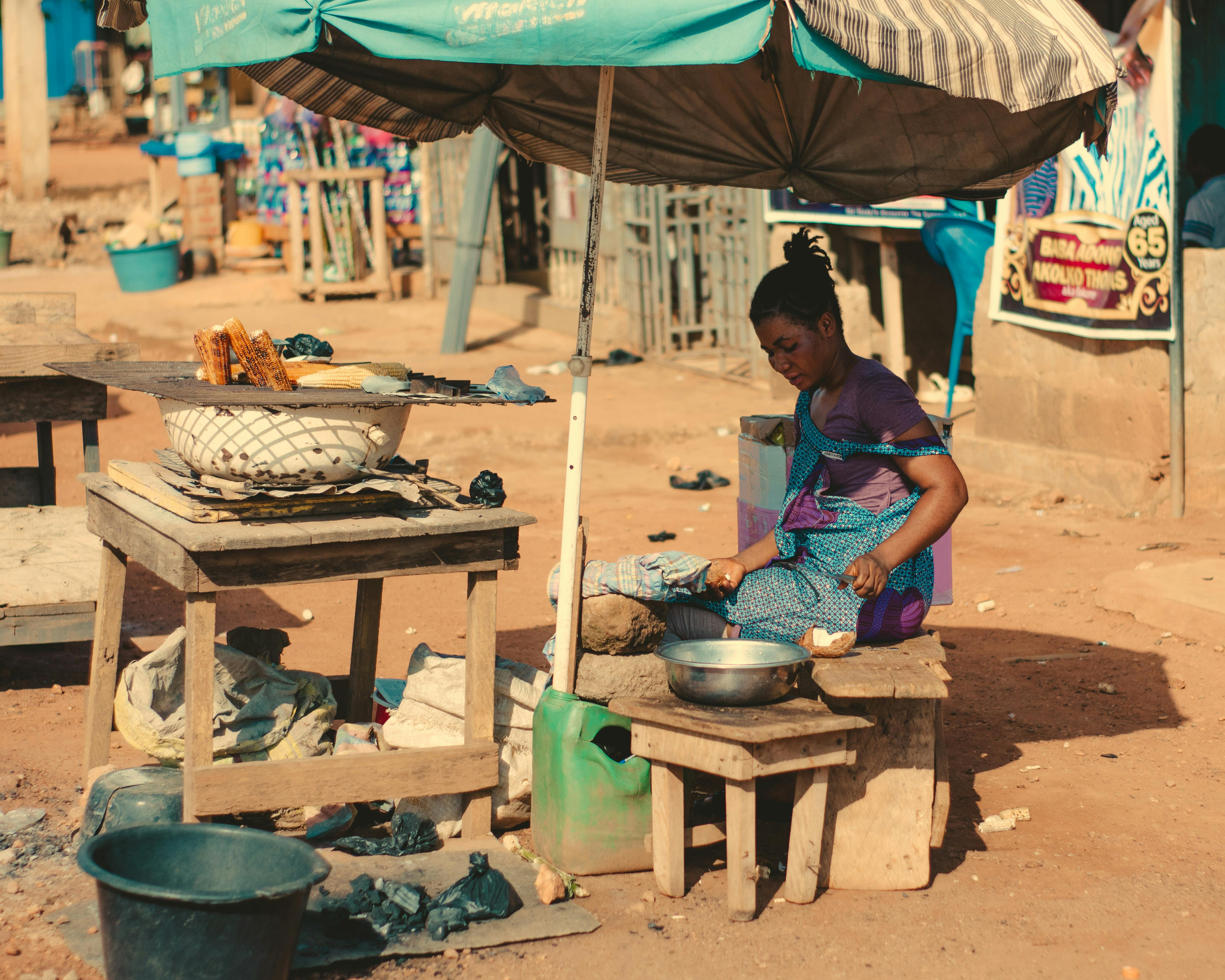 a woman is cooking food under an umbrella