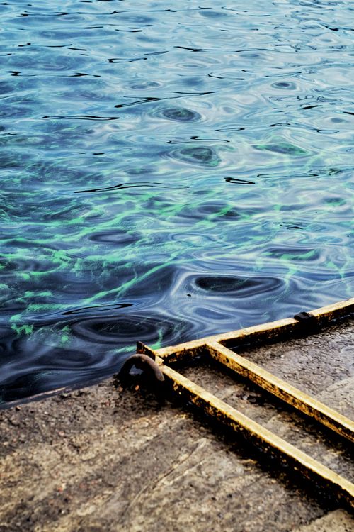 Free Artistic ripples on water with a rustic pier at the edge, showcasing intriguing reflections. Stock Photo