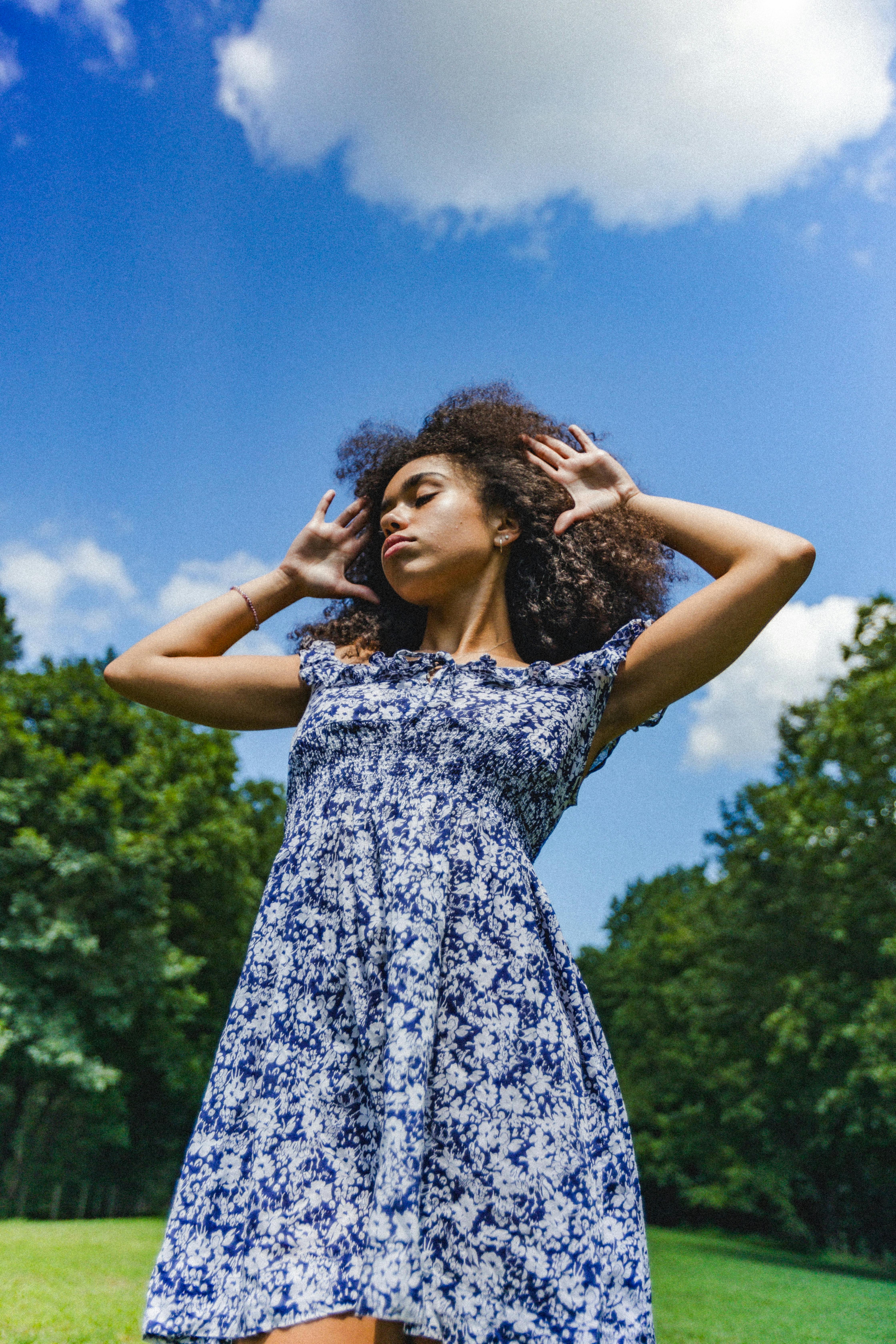 A carefree young woman enjoying a sunny day outdoors in a floral dress.