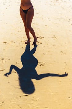 Silhouette of a woman casting a shadow on the golden sand of Pipa Beach, Brazil.