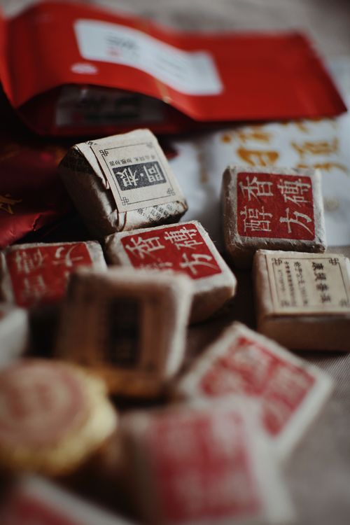 Free Close-up of assorted tea bricks with Chinese calligraphy on packaging, in a warm light setting. Stock Photo