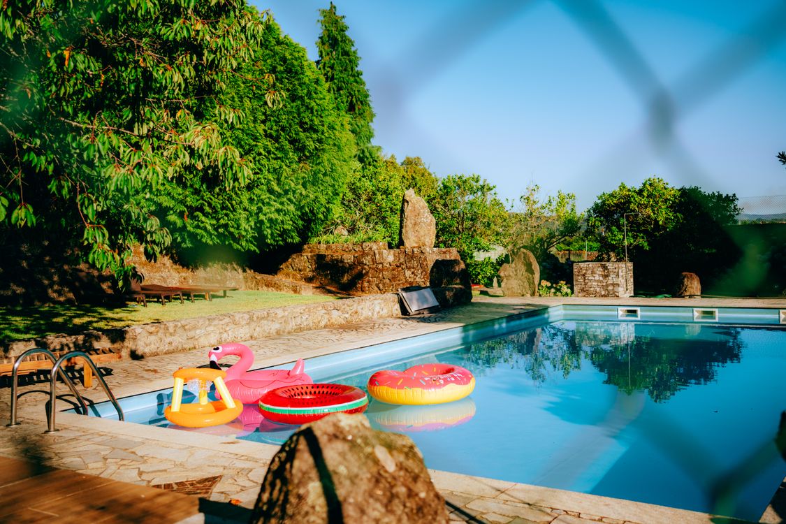 A pool with inflatable rafts and a fence · Free Stock Photo