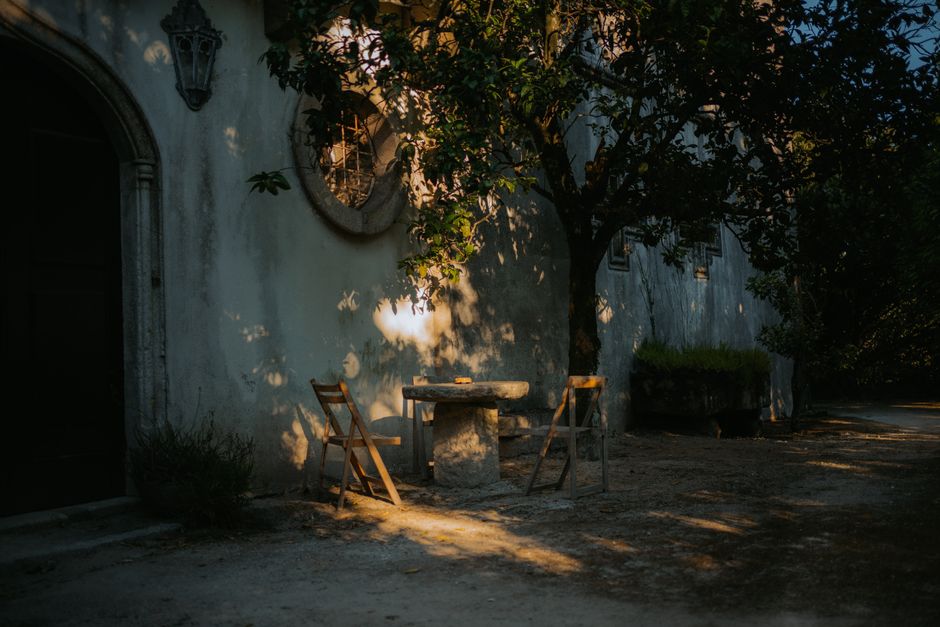 A serene outdoor scene with chairs and a table under a tree's dappled sunlight.
