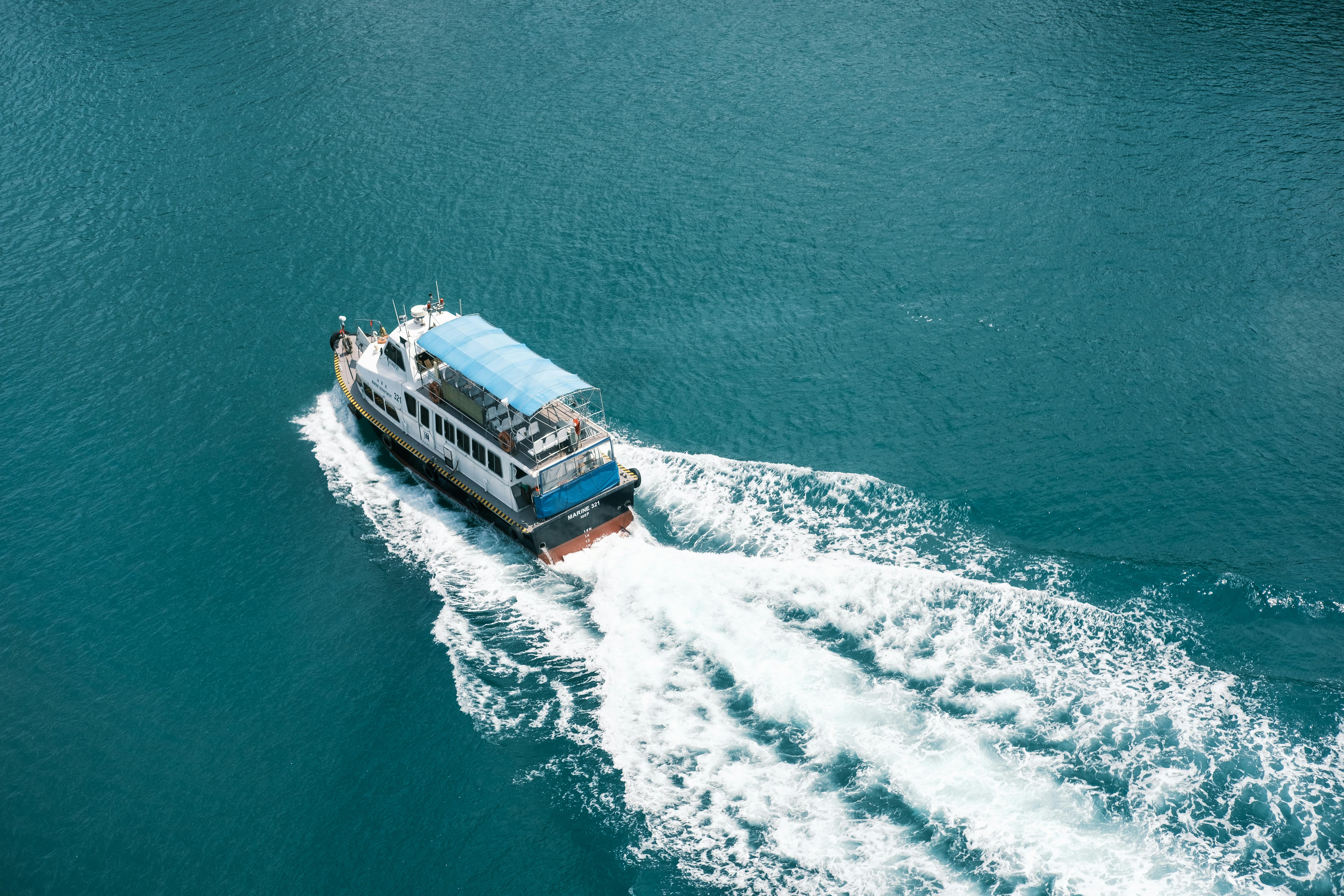 A serene ferry cruising through vivid blue ocean waters, leaving a white wake behind.