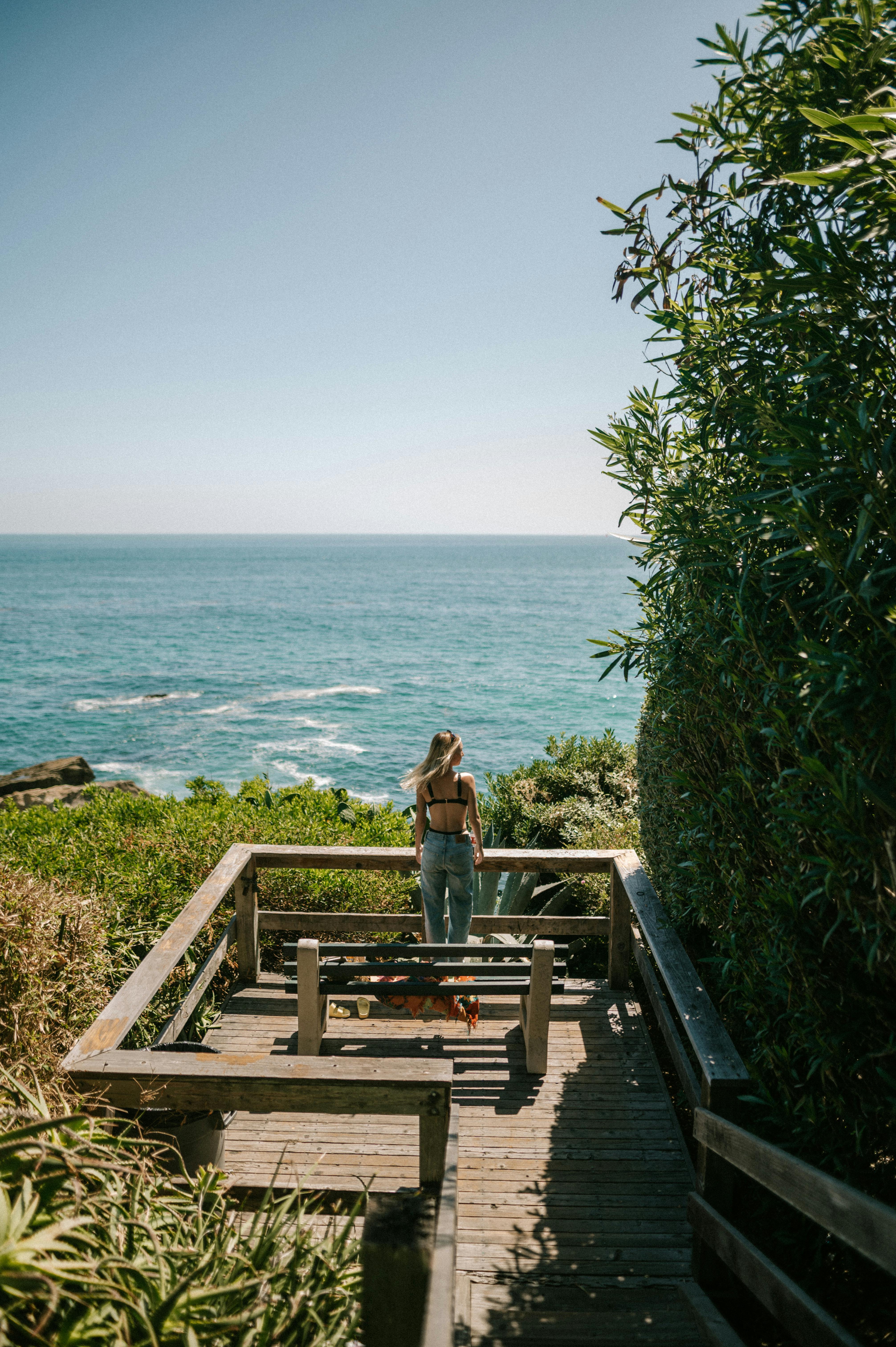 Woman enjoying a peaceful moment on a boardwalk overlooking the ocean.