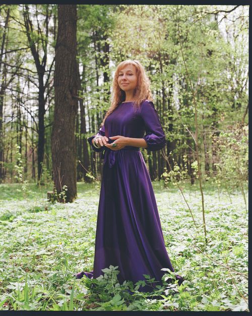 Free Portrait of a woman in a flowing purple dress surrounded by lush green forest. Stock Photo