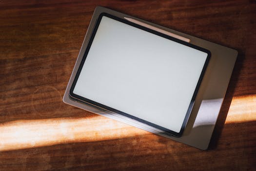 Digital tablet on a wooden desk, illuminated by sunlight from a nearby window.