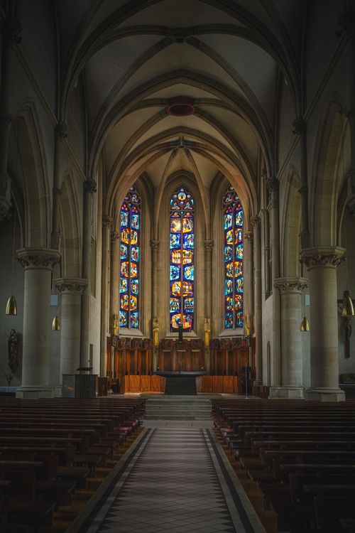 Free Dramatic gothic cathedral interior showcasing vibrant stained glass windows and gothic arches. Stock Photo