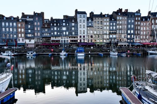 Free Charming view of Honfleur's waterfront with colorful buildings and reflections in the harbor. Stock Photo