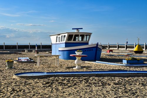 Free Quirky mini-golf course on a beach with a blue and white boat feature, under a clear sky. Stock Photo