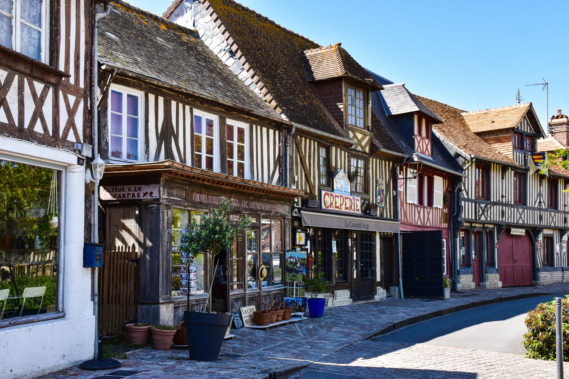 Picturesque street scene in Normandy featuring classic half-timbered houses and quaint shops.