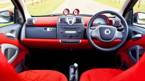 Free Detailed view of a red Smart Fortwo car's dashboard and steering wheel interior. Stock Photo