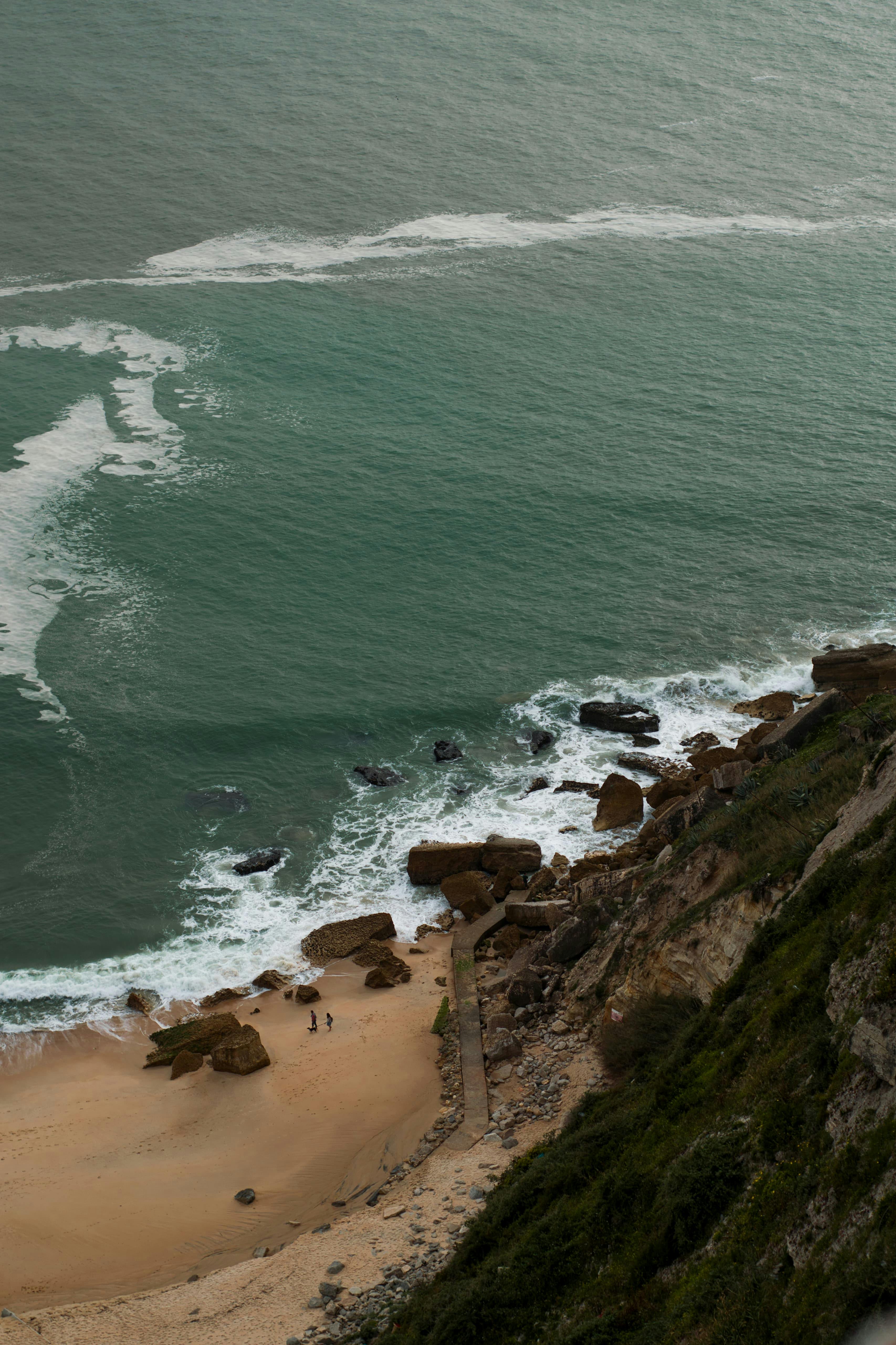 A breathtaking aerial view of a rocky seashore with waves crashing onto the beach.