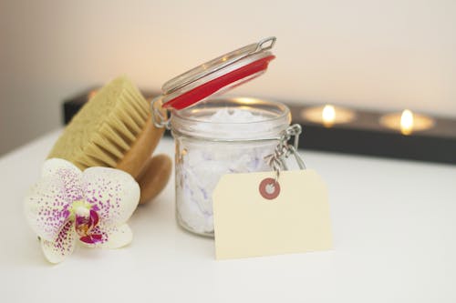Glass Jar Beside Hairbrush and White and Pink Petaled Flower