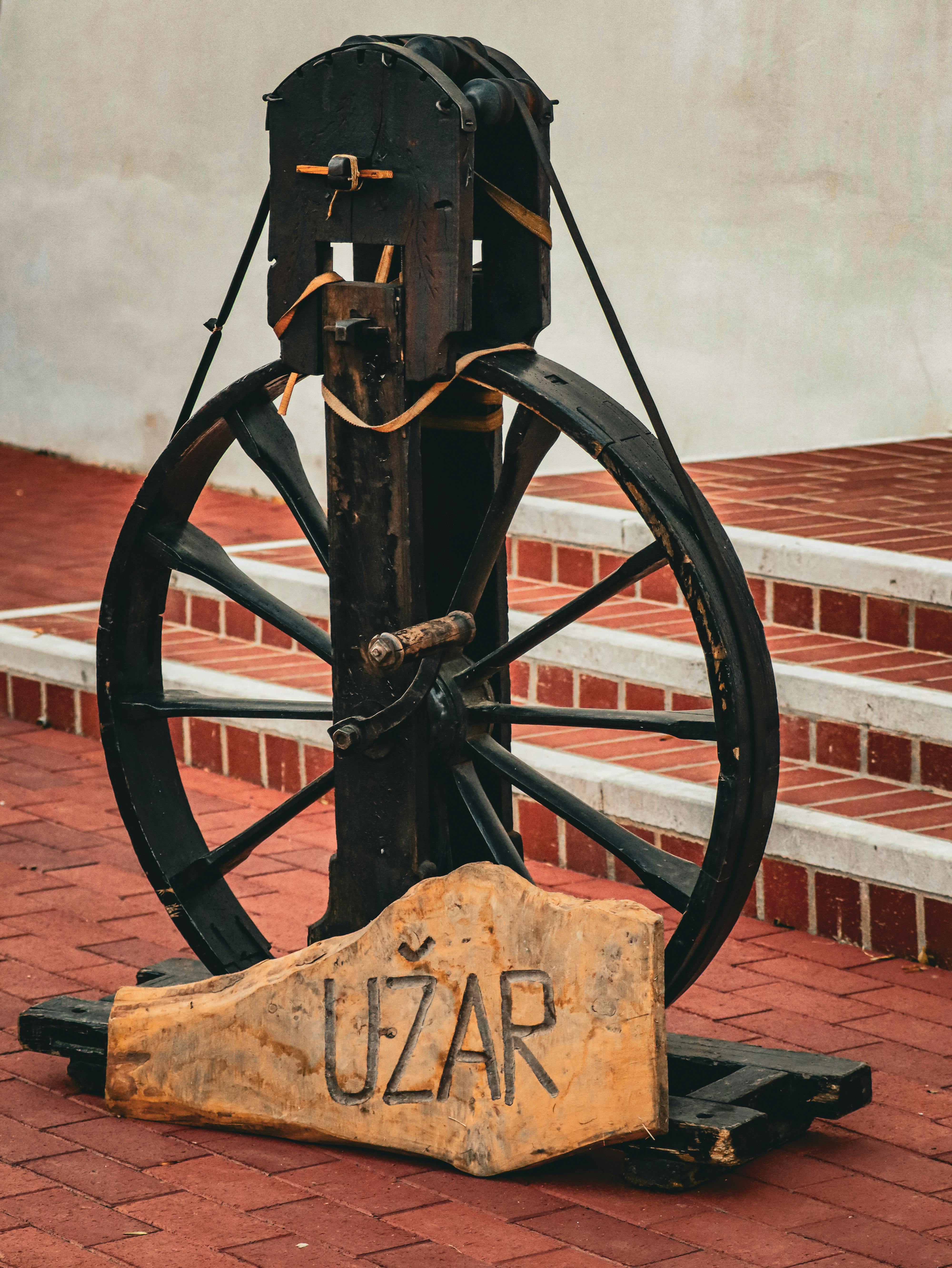 Rusty vintage industrial wheel displayed outdoors with brick steps.