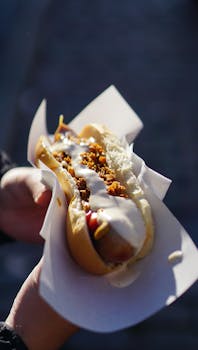 Close-up of a hot dog with creamy toppings, perfect for outdoor eating.
